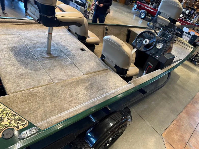 Slide: The Image of 2025 Tracker Bass Tracker Classic Limited boat with beige seats and steering console in showroom. - 2