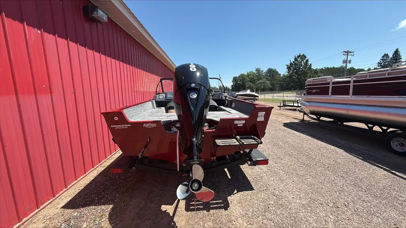 Slide: The Image of 2025 Tracker Pro Guide V-175 Combo boat, red exterior, parked outdoors near a red building. - 3