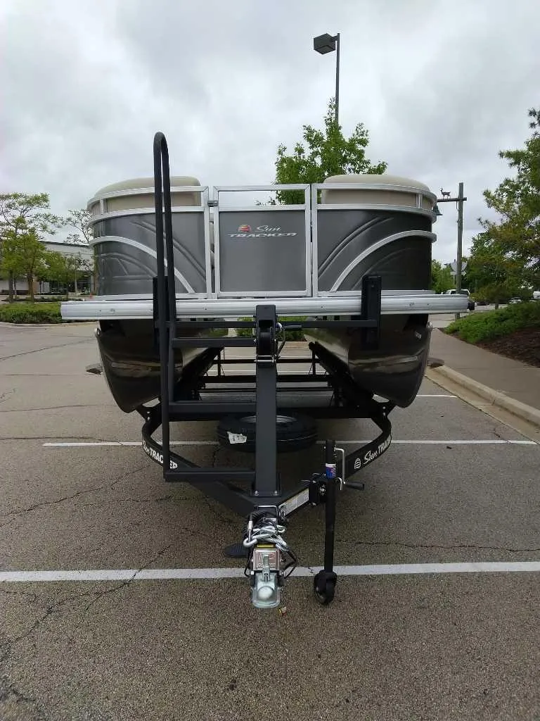 Slide: The Image of 2025 Sun Tracker Party Barge 22 RF DLX pontoon boat on trailer in parking lot. - 4
