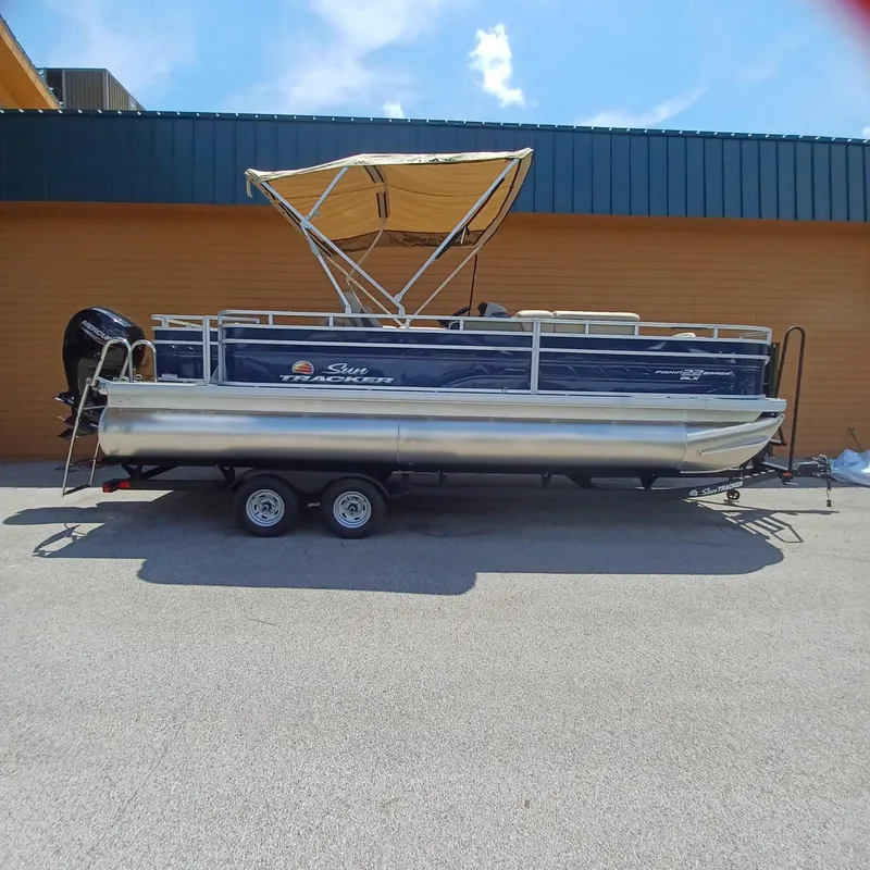 The Image of 2025 Sun Tracker Fishin' Barge 22 DLX pontoon boat with canopy on trailer. - 0