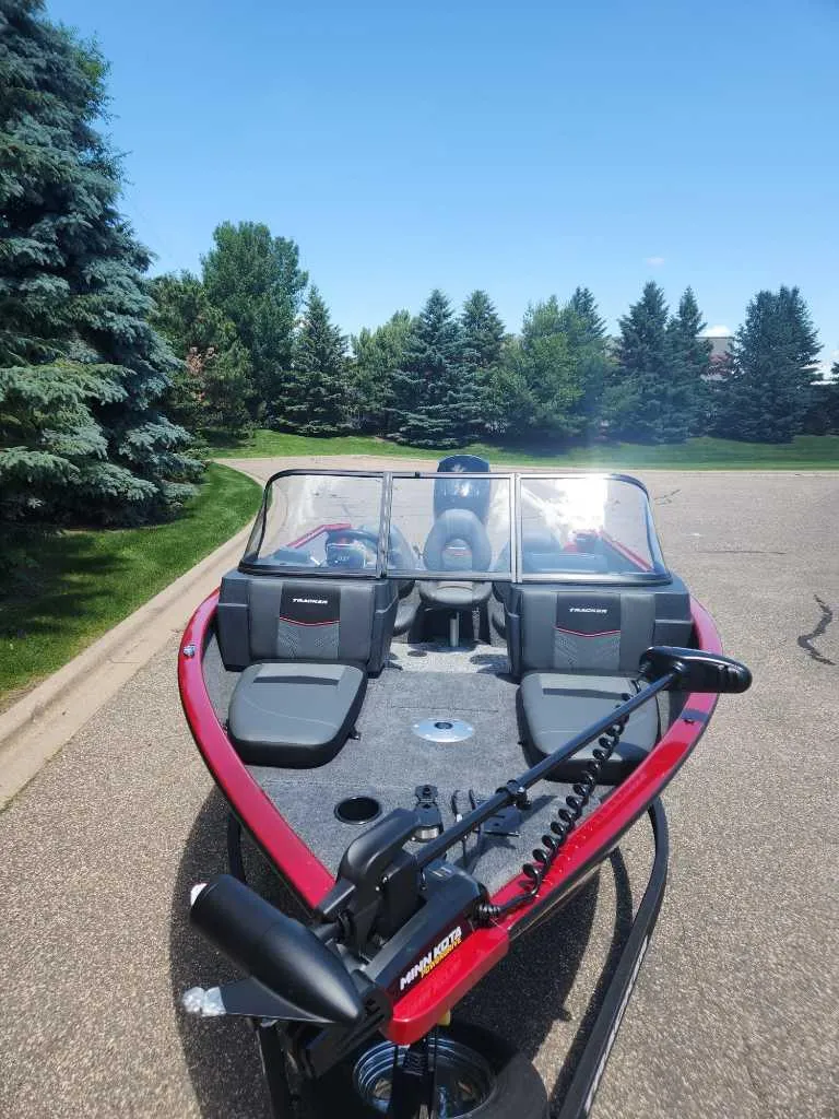 Slide: The Image of 2025 Tracker Pro Guide V-175 Combo boat on a sunny day, surrounded by trees. - 2