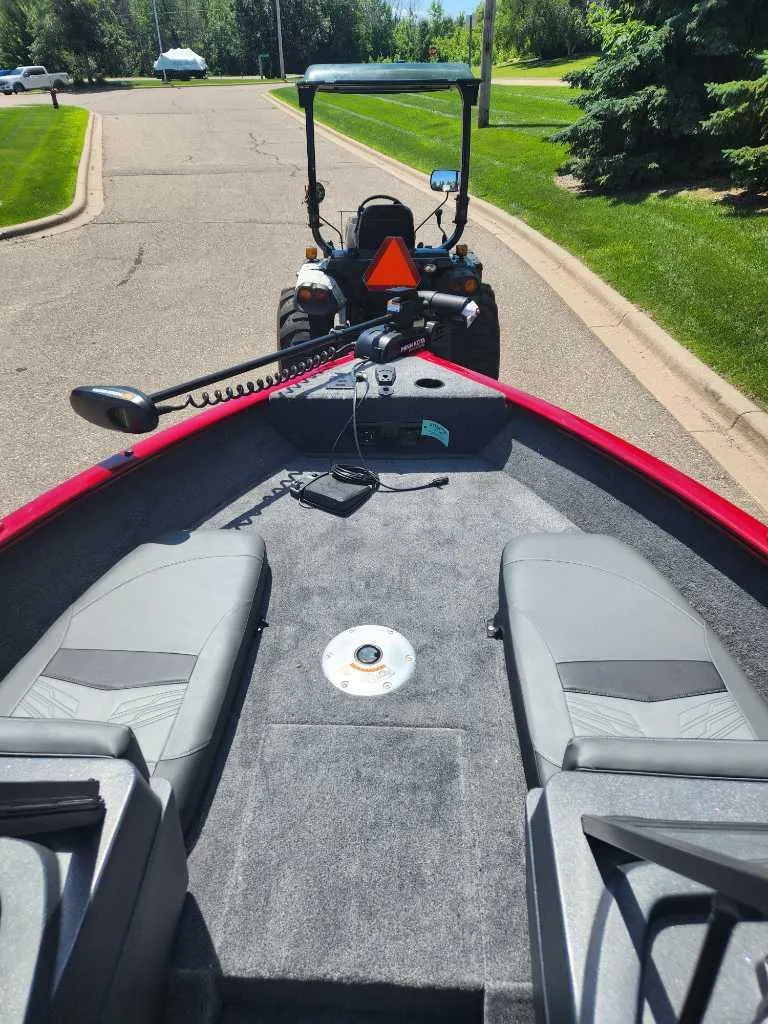 Slide: The Image of 2025 Tracker Pro Guide V-175 Combo boat interior with tractor in background on suburban street. - 3