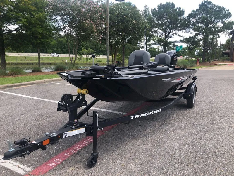 Slide: The Image of 2025 Tracker Panfish 17 boat on trailer in parking lot, surrounded by trees. - 13