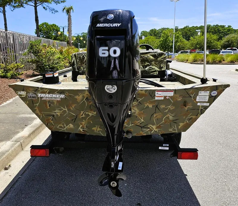 Slide: The Image of 2025 Tracker Grizzly 1754 SC boat with Mercury 60 engine, camo design, parked outdoors. - 3