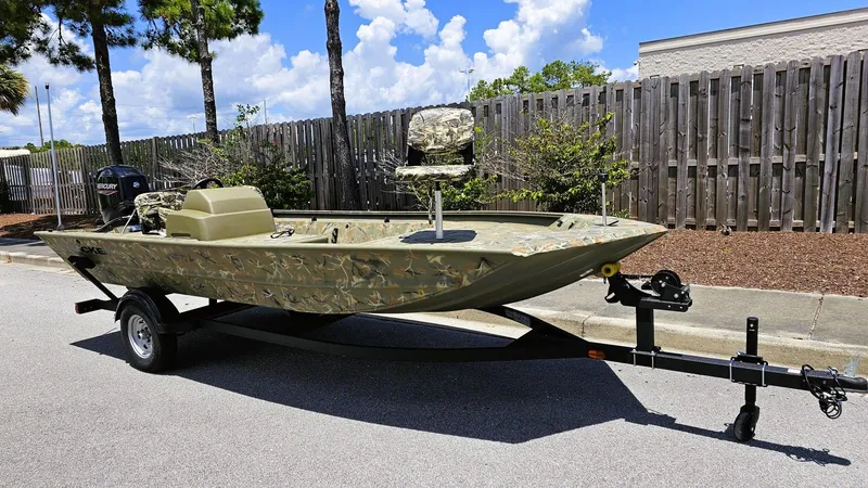 Slide: The Image of 2025 Tracker Grizzly 1754 SC boat on trailer, camo design, parked outdoors. - 4
