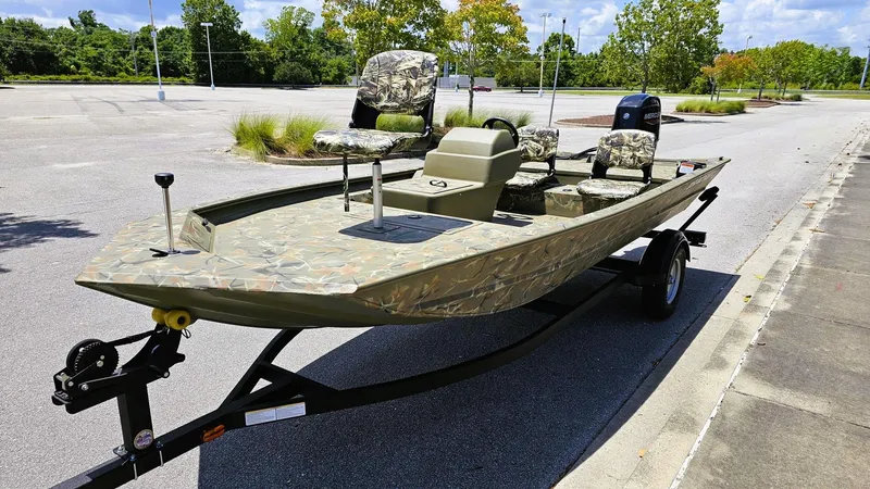 Slide: The Image of 2025 Tracker Grizzly 1754 SC boat with camouflage seats on a trailer in a parking lot. - 5