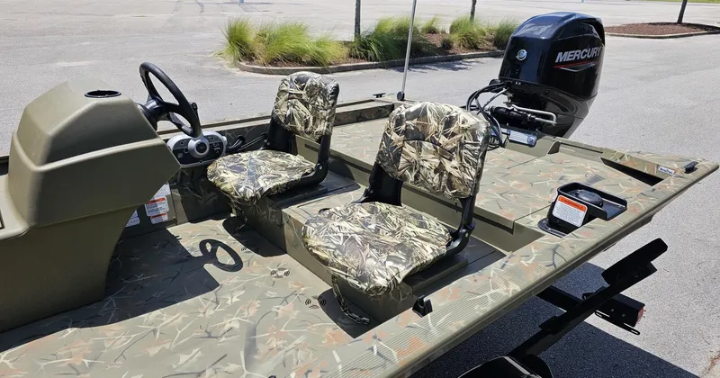 Slide: The Image of 2025 Tracker Grizzly 1754 SC boat with camo seats and Mercury outboard motor. - 7