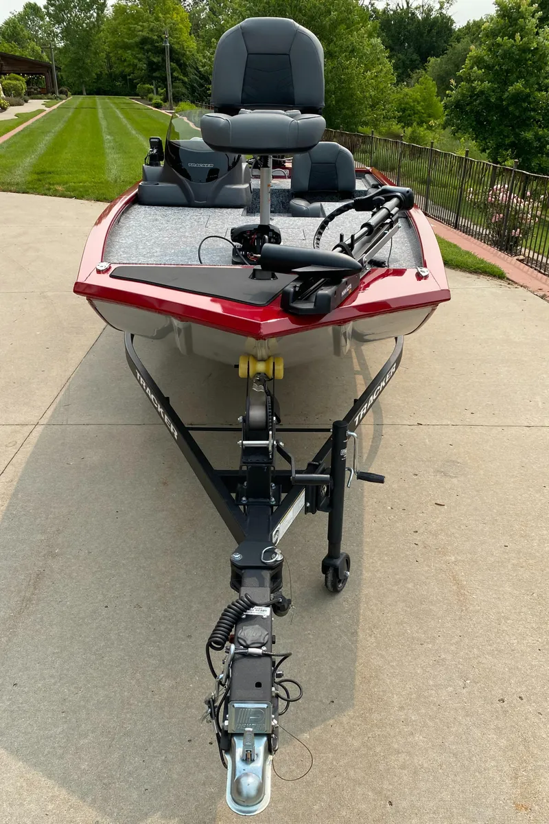 Slide: The Image of 2025 Tracker Pro 170 boat on trailer, red exterior, parked on concrete driveway. - 2