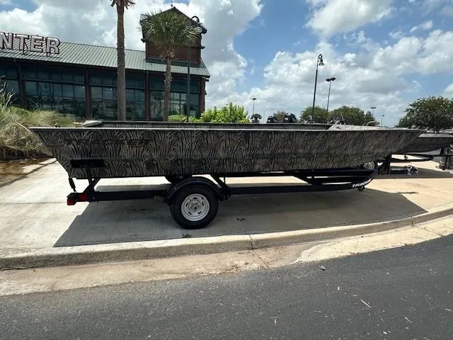 The Image of 2025 Tracker GRIZZLY 2072 Utility boat on trailer, parked outdoors under a cloudy sky. - 0