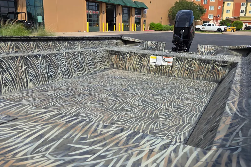 Slide: The Image of 2025 Tracker Grizzly 2072 Utility boat with camouflage interior, parked outside a building. - 13