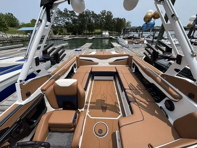 Slide: The Image of 2025 Axis Wake Research T235 boat interior with tan seating at a marina. - 10