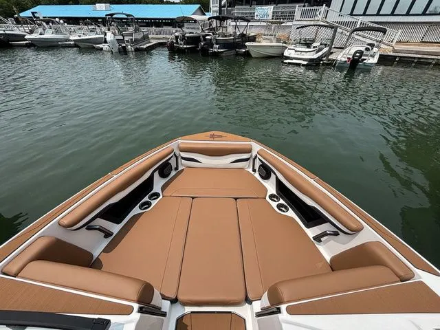 Slide: The Image of 2025 Axis Wake Research T235 boat with tan seating at a marina. - 11
