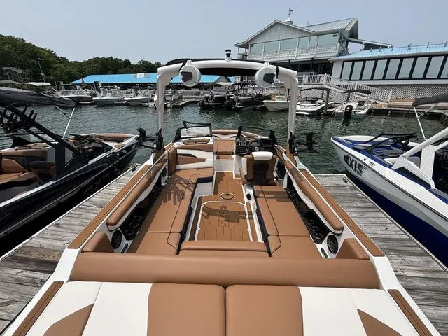 Slide: The Image of 2025 Axis Wake Research T235 boat docked at a marina, featuring spacious seating and modern design. - 4