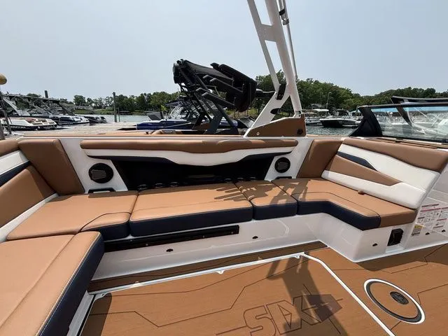 Slide: The Image of 2025 Axis Wake Research T235 boat interior with tan and white seating, docked at marina. - 6