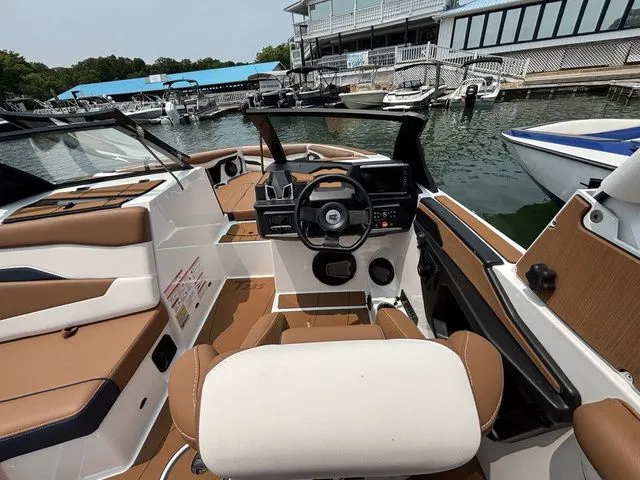 Slide: The Image of 2025 Axis Wake Research T235 boat interior at marina, featuring modern dashboard and seating. - 8