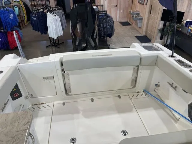 Slide: The Image of 2025 Boston Whaler 240 Vantage boat interior, showcasing seating and storage in a showroom setting. - 12