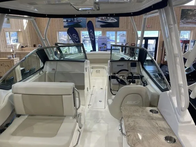 Slide: The Image of 2025 Boston Whaler 240 Vantage interior with seating and helm, showcased in a boat showroom. - 7
