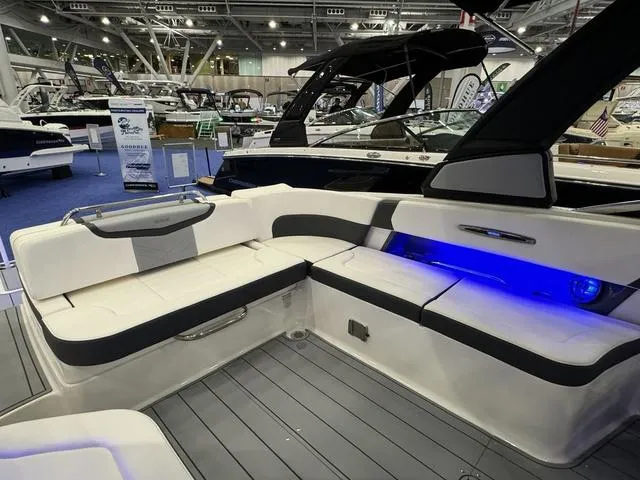 Slide: The Image of 2024 Chaparral 307 SSX boat interior with sleek seating and blue LED lighting at a boat show. - 10