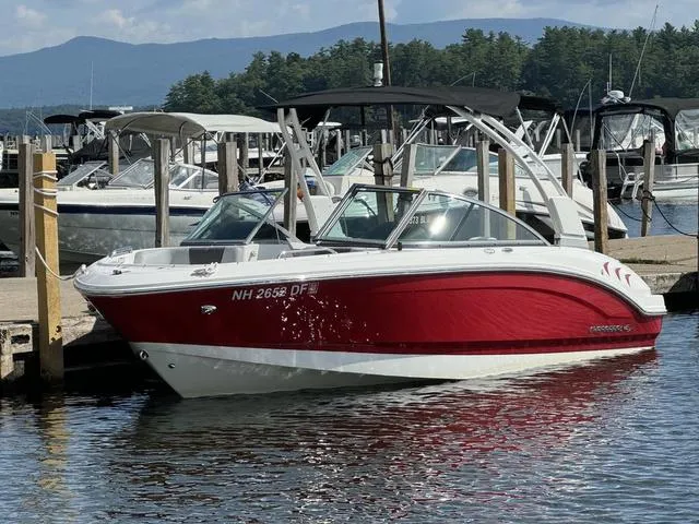 Slide: The Image of 2024 Chaparral 21 SSi boat docked, red and white design, calm water, scenic background. - 1