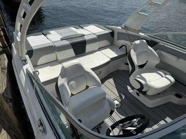 Slide: The Image of 2024 Chaparral 21 SSi boat interior with white seating and steering wheel, docked by water. - 6