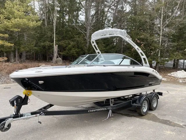 Slide: The Image of 2024 Chaparral 21 SSi boat on trailer, parked outdoors with forest background. - 1