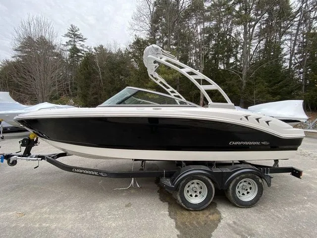 Slide: The Image of 2024 Chaparral 21 SSi boat on trailer, black and white design, parked outdoors. - 2