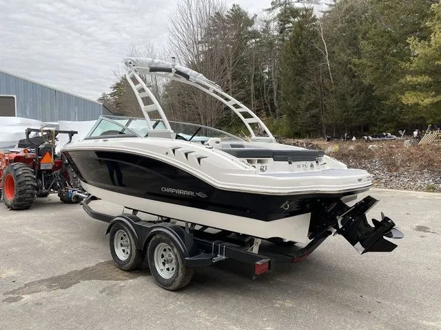 Slide: The Image of 2024 Chaparral 21 SSi boat on trailer, parked outdoors near trees and a tractor. - 3