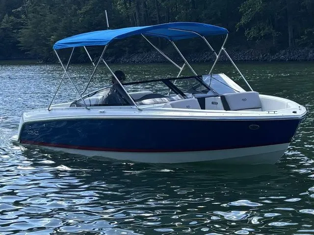 Slide: The Image of 2024 Cobalt CS22 boat with blue canopy cruising on a serene lake. - 1