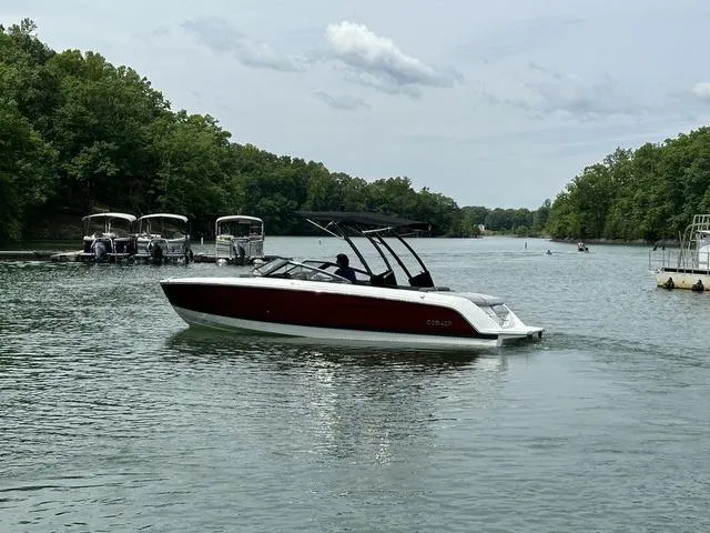 Slide: The Image of 2024 Cobalt CS23 boat cruising on a scenic lake with lush green trees. - 3