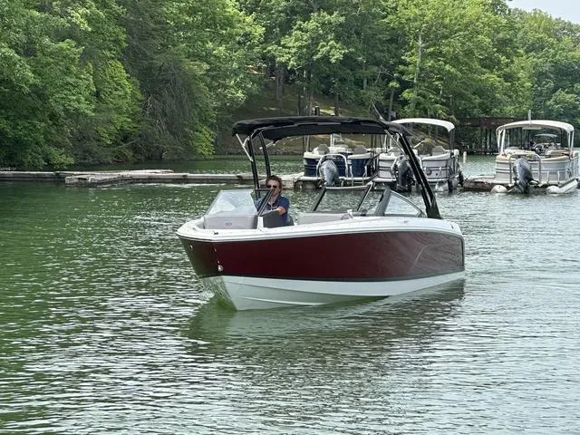 Slide: The Image of 2024 Cobalt CS23 boat cruising on a serene lake with lush green surroundings. - 4