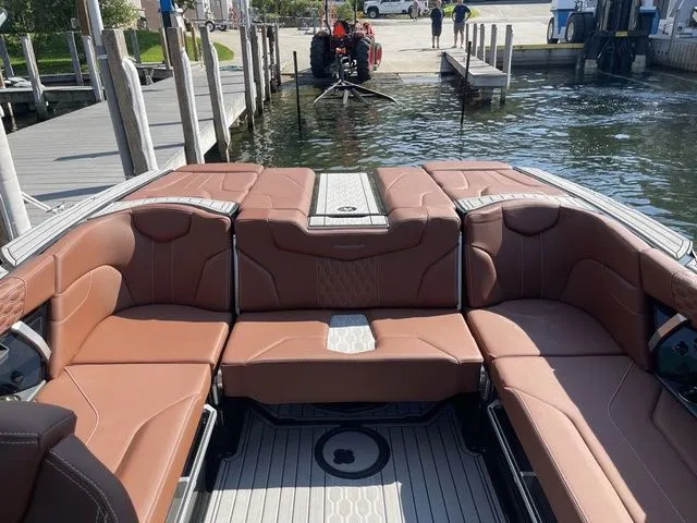 Slide: The Image of 2024 MasterCraft XT22 T boat with luxurious brown seating at a dock. - 11