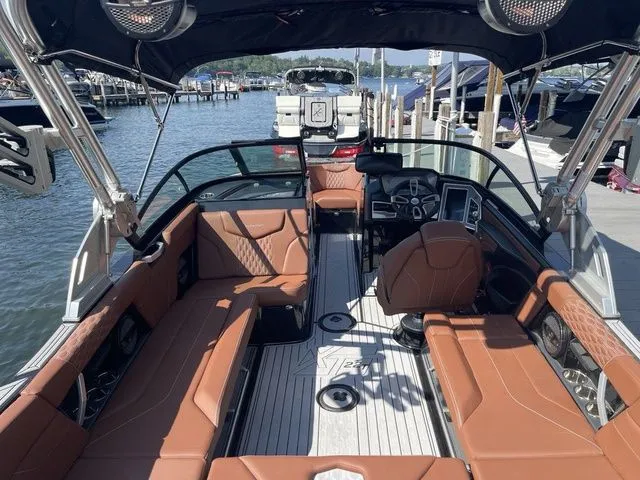 Slide: The Image of 2024 MasterCraft XT22 T boat interior with brown seating, docked at a marina. - 13