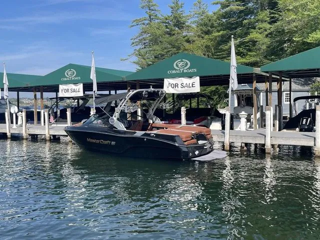 Slide: The Image of 2024 MasterCraft XT22 T boat docked, for sale at marina with green canopies. - 3
