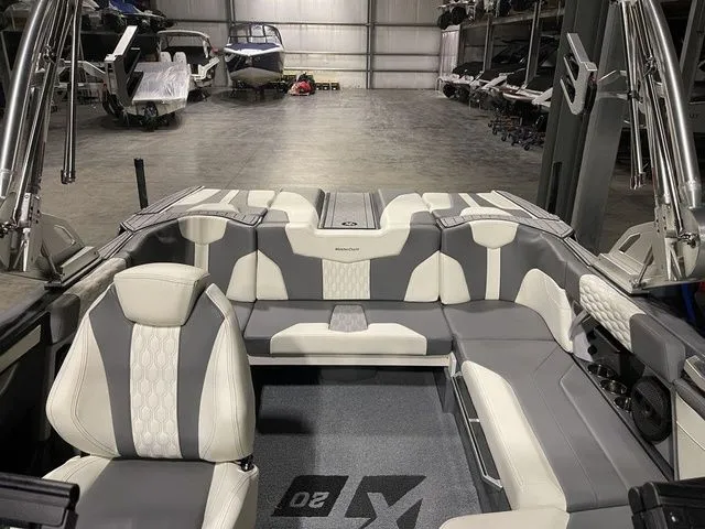 Slide: The Image of 2024 MasterCraft XT20 boat interior with gray and white seating in a storage facility. - 12