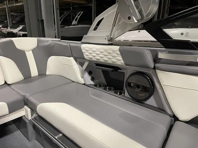 Slide: The Image of 2024 MasterCraft XT20 boat interior with gray and white seating, cup holders, and speaker system. - 13