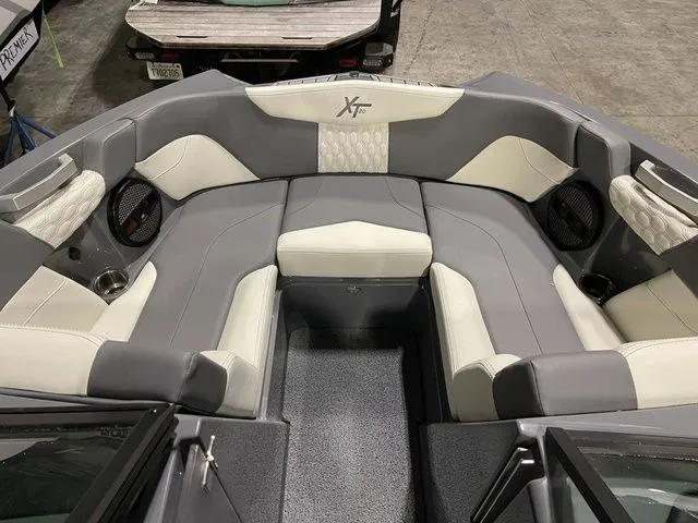 Slide: The Image of 2024 MasterCraft XT20 boat interior with gray and white seating, featuring premium upholstery and speakers. - 17