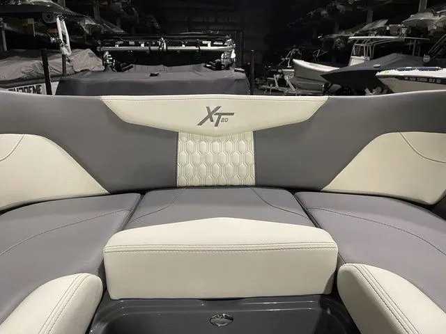 Slide: The Image of 2024 MasterCraft XT20 boat interior with gray and white seating in a showroom. - 18