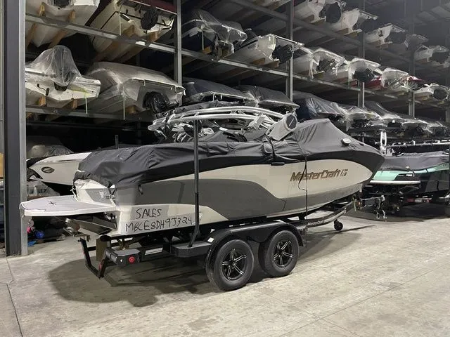 Slide: The Image of 2024 MasterCraft XT20 boat covered in storage, on a trailer, in a warehouse. - 5