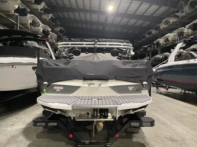 Slide: The Image of 2024 MasterCraft XT20 boat in storage, rear view with cover, surrounded by other boats. - 7