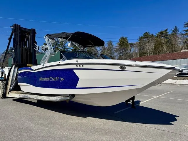Slide: The Image of 2022 MasterCraft XStar boat on a forklift, parked outdoors under clear blue sky. - 1