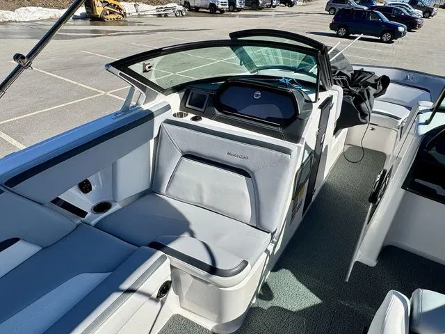 Slide: The Image of 2022 MasterCraft XStar boat interior with sleek seating and modern dashboard in a parking lot. - 25