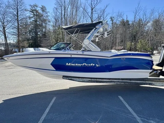 Slide: The Image of 2022 MasterCraft XStar boat in blue and white, parked outdoors on a sunny day. - 6