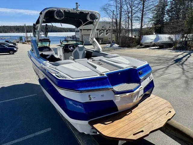 Slide: The Image of 2022 MasterCraft XStar boat with blue and white design, parked near a lake. - 8