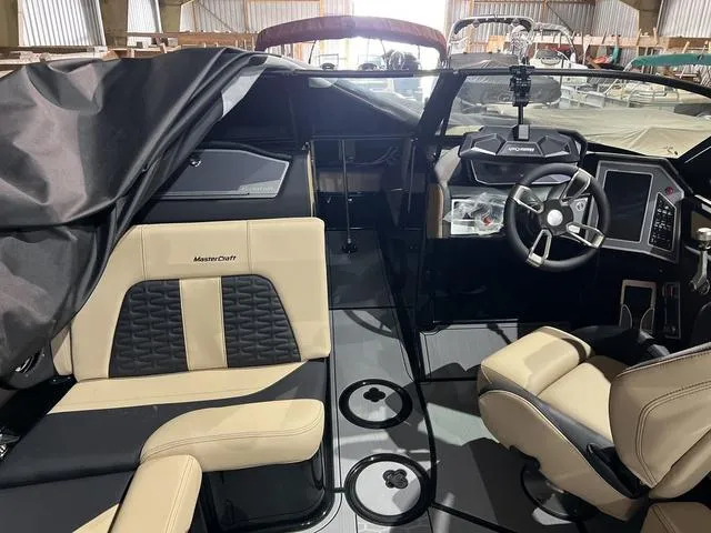 Slide: The Image of 2024 MasterCraft X24 boat interior with beige and black seating, modern dashboard, and steering wheel. - 5
