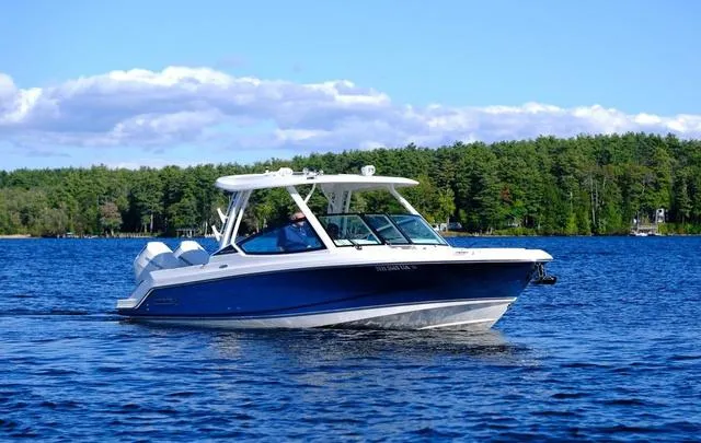 Slide: The Image of 2024 Boston Whaler 280 Vantage boat cruising on a lake with forested shoreline. - 10