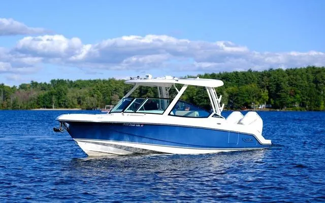 Slide: The Image of 2024 Boston Whaler 280 Vantage boat on a serene lake with a forested background. - 12