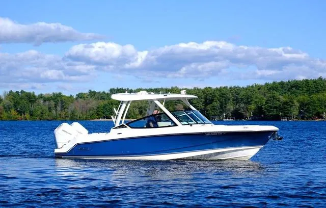 Slide: The Image of 2024 Boston Whaler 280 Vantage boat cruising on a serene lake under a clear blue sky. - 13