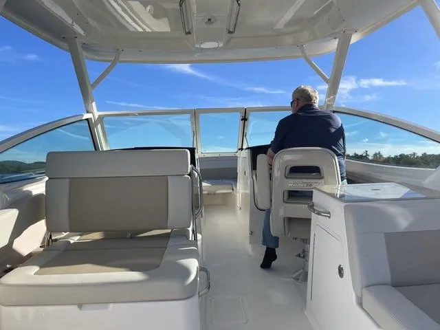 Slide: The Image of 2024 Boston Whaler 280 Vantage boat interior with seating and helm, under clear blue sky. - 17