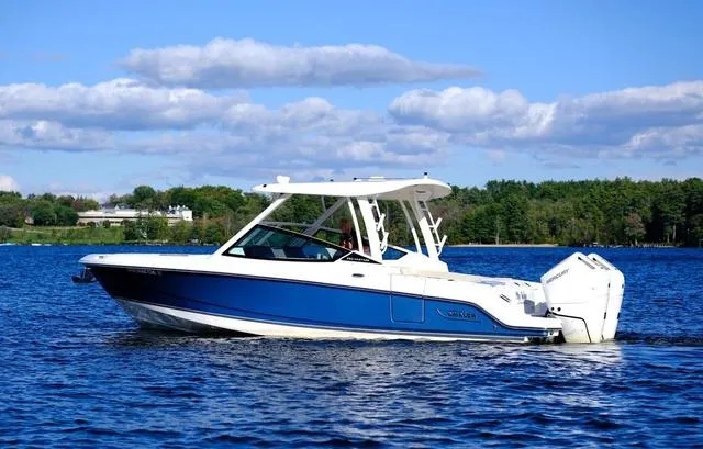Slide: The Image of 2024 Boston Whaler 280 Vantage boat cruising on a serene lake under a blue sky. - 3