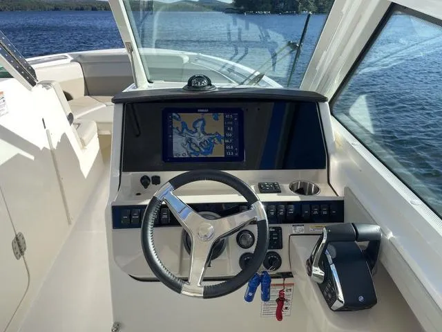 Slide: The Image of 2024 Boston Whaler 280 Vantage helm with navigation display, steering wheel, and throttle controls. - 31